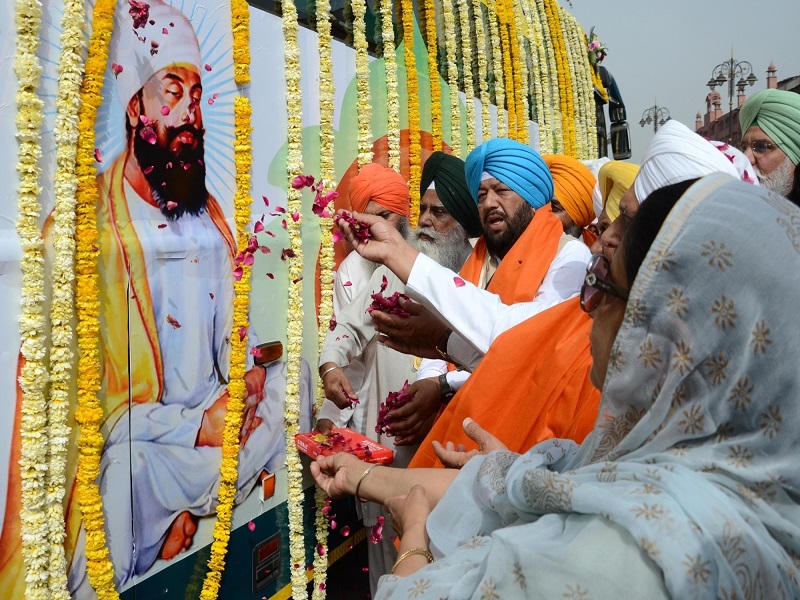 श्री गुरु तेग बहादुर जी के चित्र पर गुलाब की पंखुड़ियों डालते सिख श्रद्धालु