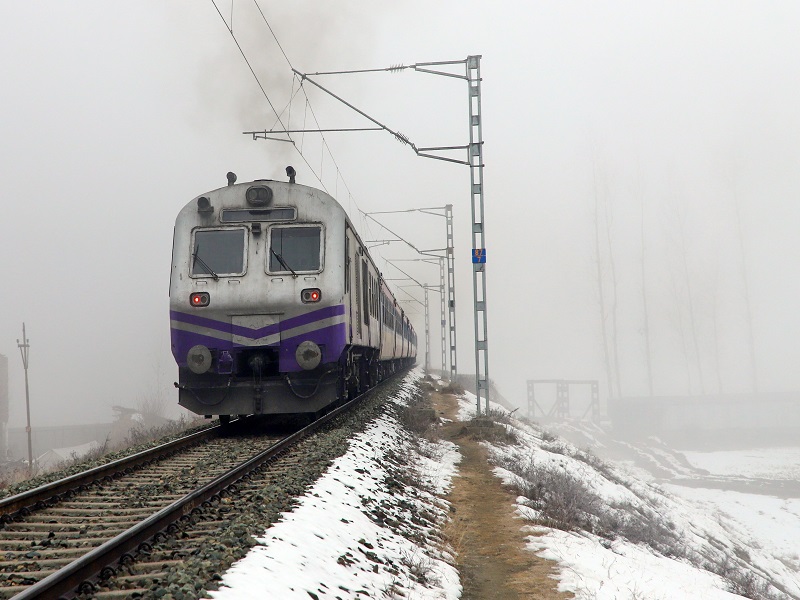 Baramulla: A train runs on a track as the surroundings are covered in snow on a cold winter morning in Baramulla on Friday, January 3, 2025. (Photo: IANS/Nisar Malik)